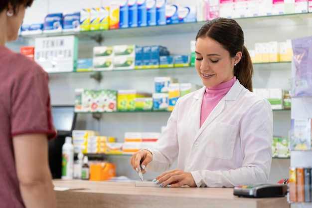 farmacéutica cortando el código de barras de un medicamento en el mostrador con un cliente