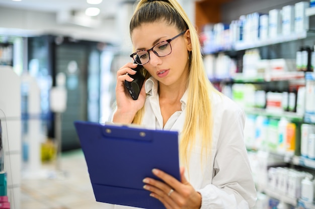 Farmacêutica falando ao telefone com um cliente em sua loja