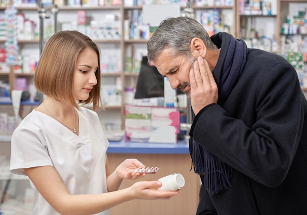 Farmacêutico, ajudando o homem com dor de dente na farmácia.