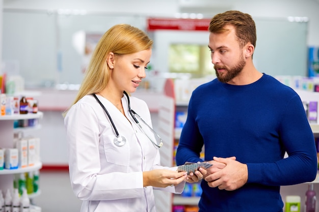 Farmacéutico amigable caucásico tiene una agradable conversación con un cliente