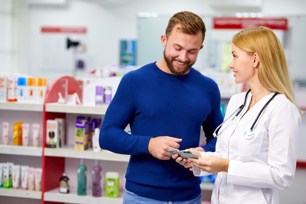 Farmacéutico amigable caucásico tiene una agradable conversación con un cliente