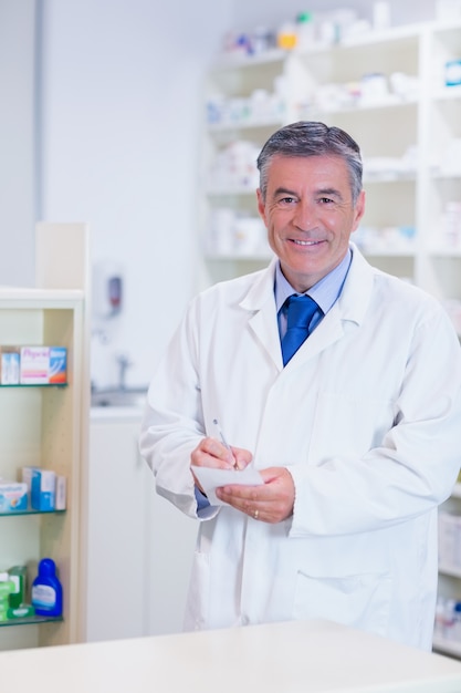 Farmacéutico con cabello gris escribiendo notas