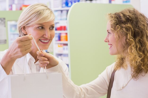 Farmacéutico y cliente con bolsa de papel