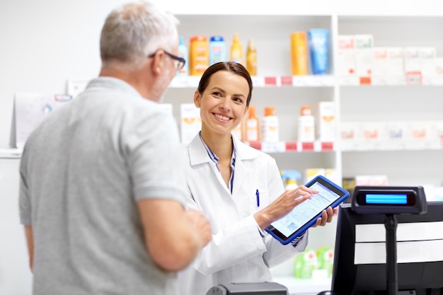 Foto farmacéutico y cliente con tableta en la farmacia