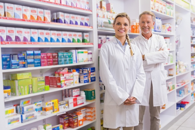 Foto farmacêutico com seu estagiário permanente e sorrindo para a câmera