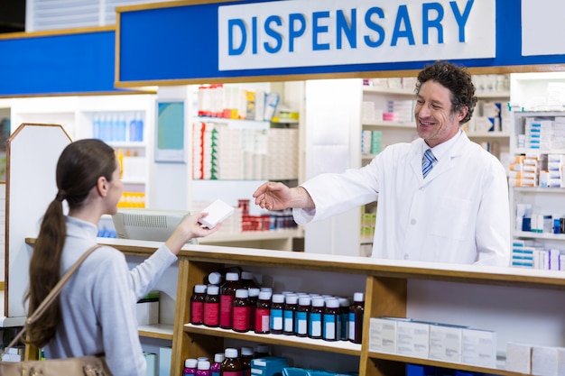 Farmacêutico dando caixa de medicamento para o cliente