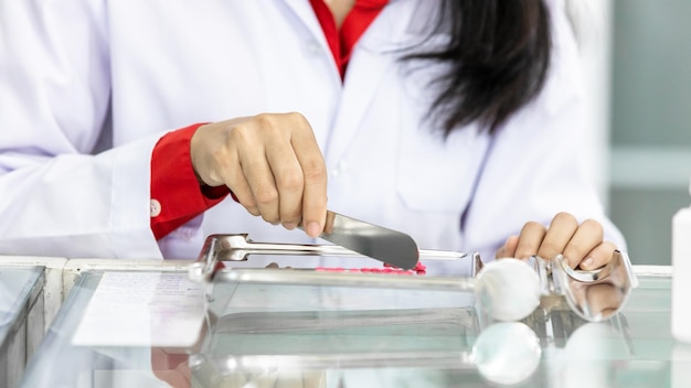 Farmacêutico de mulher asiática contando comprimidos na farmácia com bandejas de contagem de comprimidos de aço inoxidável Prepare o pacote de medicamentos para o paciente na farmácia farmácia saudável e remédios