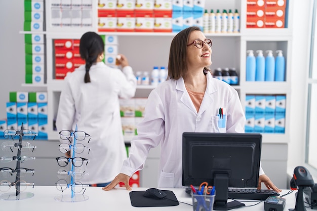 Farmacéutico de dos mujeres que usa la computadora que trabaja en la farmacia