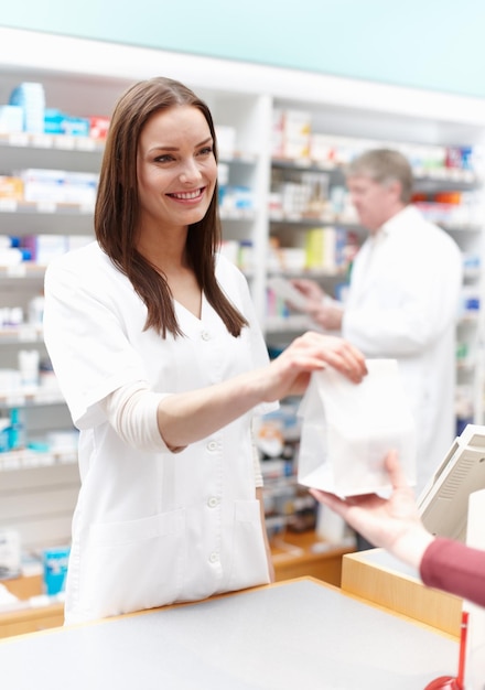 Foto farmacéutico entregando el paquete al cliente retrato de farmacéutico entregando el paquete al cliente en la tienda médica