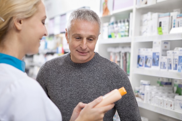 Farmacêutico fêmea adorável que ajuda seu cliente