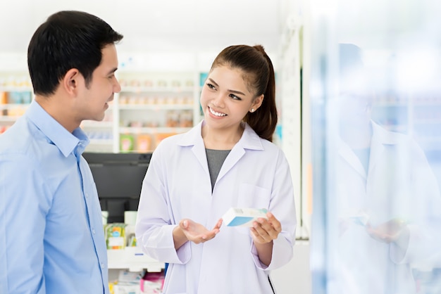 Farmacêutico fêmea asiático bonito com cliente em uma farmácia.