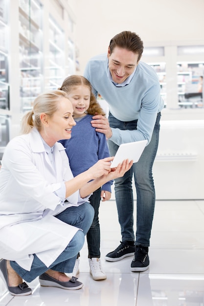 Farmacéutico femenino ayudando a una familia en una farmacia