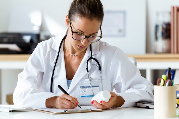 Farmacéutico femenino hermoso que sostiene el tarro de píldoras en manos.