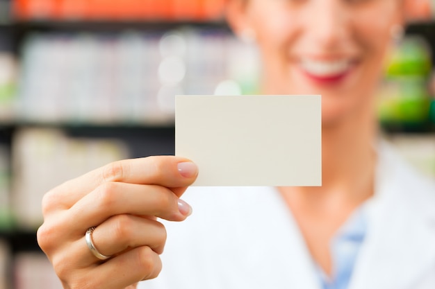 Farmacéutico femenino con tarjeta de visita en farmacia