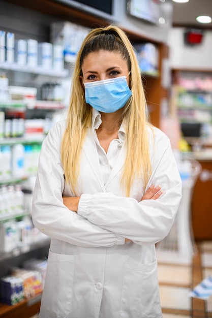 Farmacêutico feminino com máscara protetora no rosto, trabalhando na farmácia. Conceito de saúde médica.