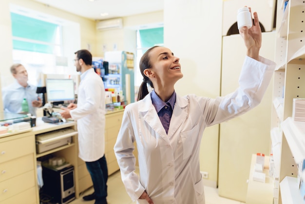 Farmacêutico feminino está a considerar embalagem de comprimidos.