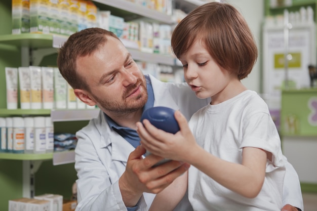 Farmacéutico masculino maduro ayudando a niño en la farmacia