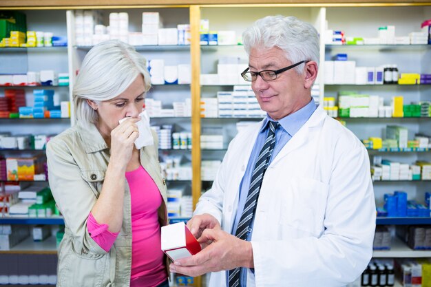 Farmacêutico, mostrando o medicamento ao cliente