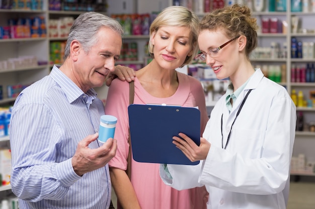 Farmacêutico mostrando prancheta para clientes