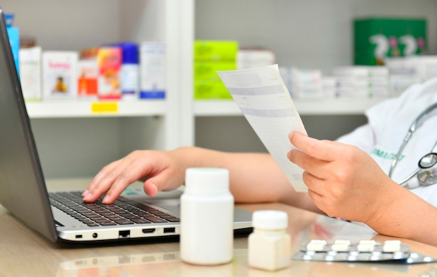 Farmacéutico con el ordenador portátil en la farmacia