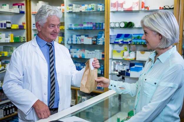 Farmacêutico que dá o pacote do medicamento ao cliente