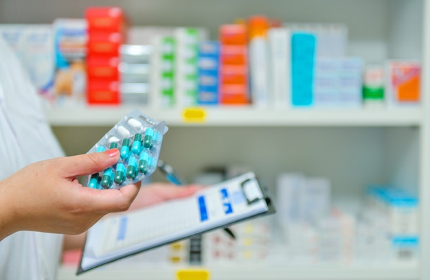 Foto farmacéutico que llena la prescripción en una farmacia de farmacia borrosa