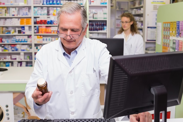 Farmacéutico que mira la botella de la medicina