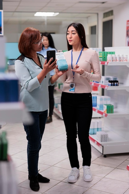 Farmacéutico que trabaja en una farmacia con un cliente anciano, ayudando a la mujer a encontrar una caja de medicamentos recetados en los estantes de la farmacia. Cliente preguntando a especialista sobre pastillas en farmacia farmacéutica.