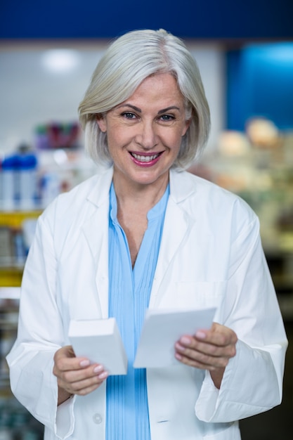 Farmacêutico, segurando o medicamento e prescrição em farmácia