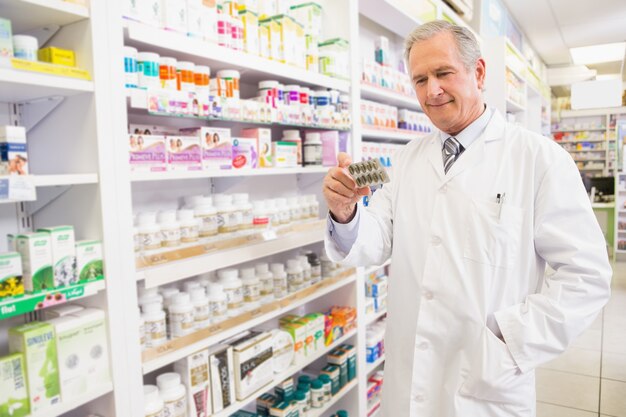 Farmacéutico senior sonriente que sostiene la ampolla