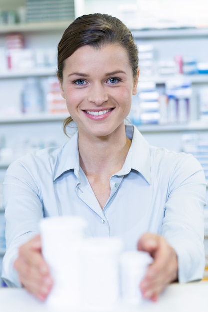 Farmacéutico sonriente que sostiene el envase de la medicina en farmacia