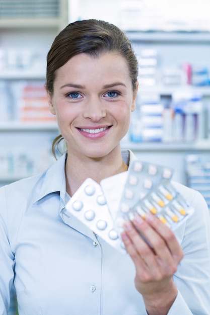 Foto farmacêutico sorridente, mostrando o medicamento na farmácia