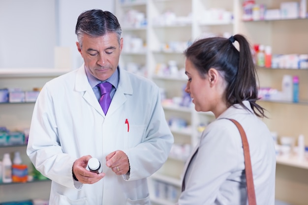 Farmacéutico sosteniendo una botella de drogas hablando con el cliente