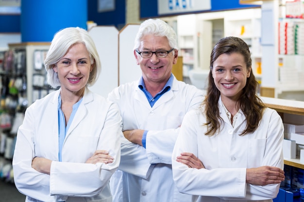 Farmacéuticos sonrientes de pie con los brazos cruzados en farmacia