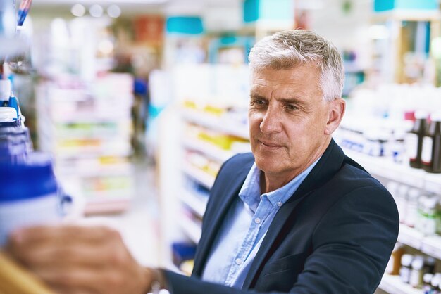 Farmacia de hombre mayor o cliente que busca medicamentos de píldoras de atención médica al por menor en farmacia Buscando hombre de negocios o cliente maduro revisando o eligiendo medicamentos o vitaminas médicas en el estante
