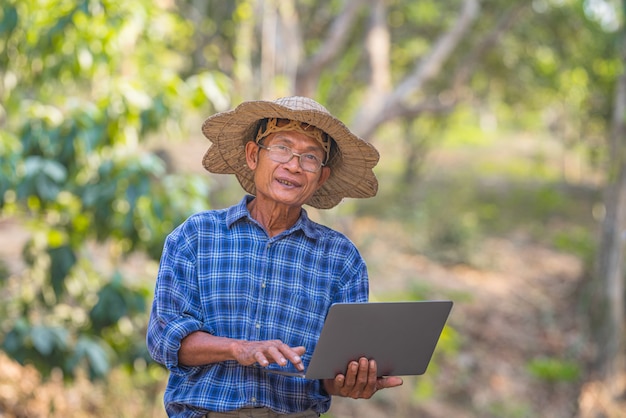 Farmer Asian mit Smartphone und Laptop, Business- und Technologiekonzept