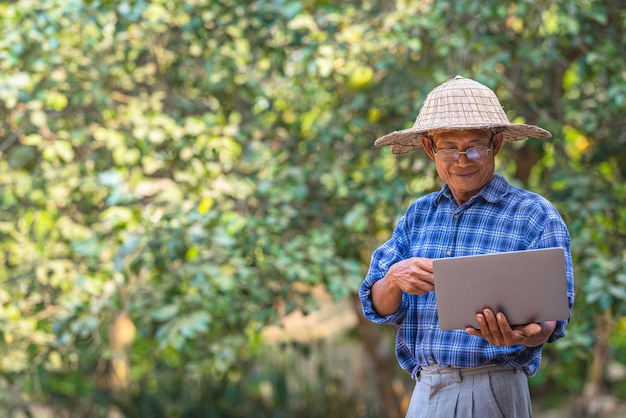 Farmer Asian con teléfono inteligente y computadora portátil, concepto de negocio y tecnología