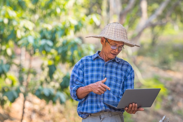 Farmer Asian con teléfono inteligente y computadora portátil