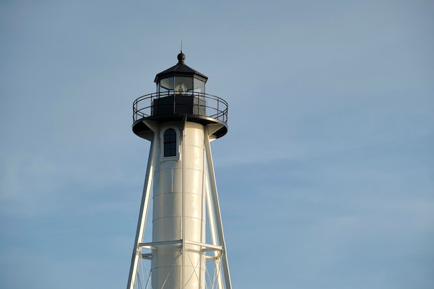 Faro alto blanco en la orilla del mar contra el cielo azul para la navegación de embarcaciones comerciales