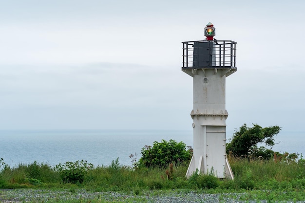 Faro automático con luz de sector en un cabo alto sobre el puerto marítimo