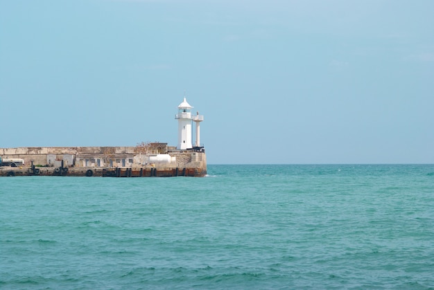 Faro en la bahía con mar y cielo.