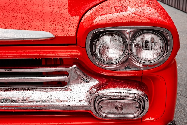 Faro de un coche retro en gotas de lluvia.