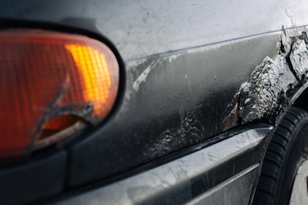 Un faro de coche roto con rastros de reparación Enfoque selectivo en el guardabarros del coche