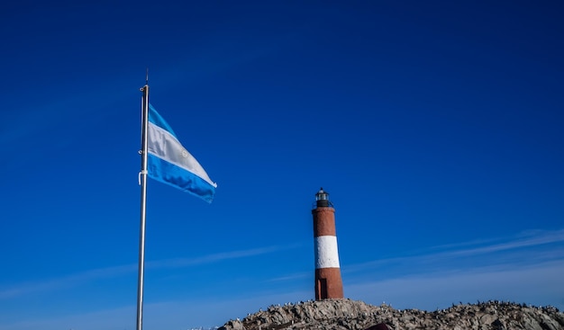 Foto faro les eclaireurs de ushuaia con bandera argentina