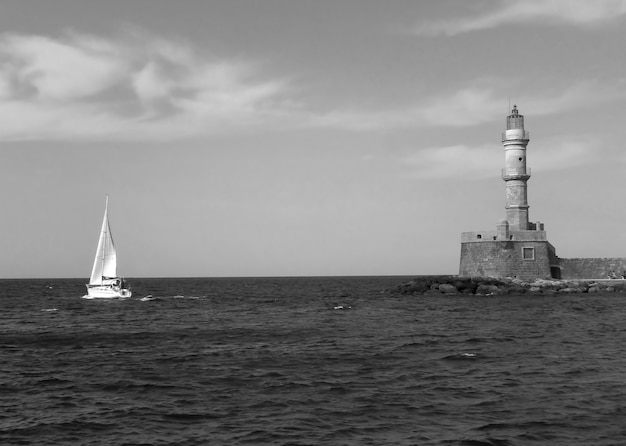 Faro histórico del puerto viejo de Chania con un velero en la isla de Creta Grecia en monocromo