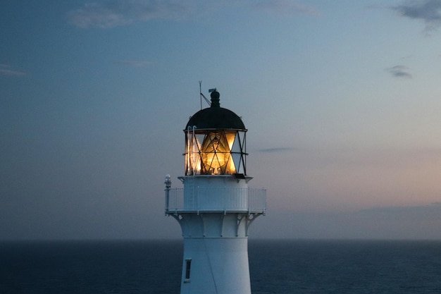Faro iluminado en la playa contra el cielo