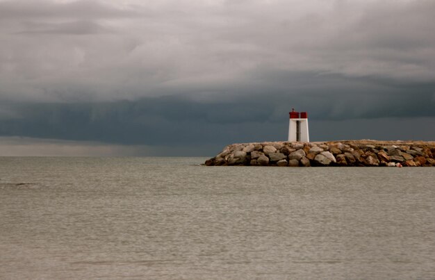 Foto faro junto al río contra el cielo nublado