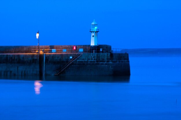 Foto faro por el mar contra el cielo al anochecer