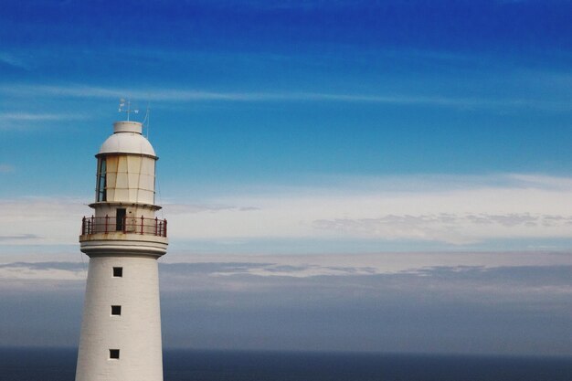 Faro por el mar contra el cielo azul