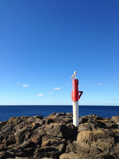 Foto faro por el mar contra el cielo azul